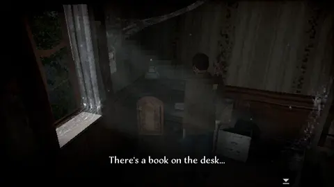 Game screenshot. Character stands in dark spooky room front of table. Comment: There's a book on the desk...